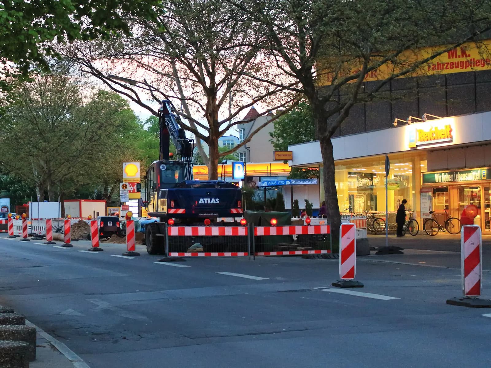 Abgesicherte Fahrbahnbaustelle mit Leitbaken, Absperrschranken und Warnleuchten vor einem Bagger